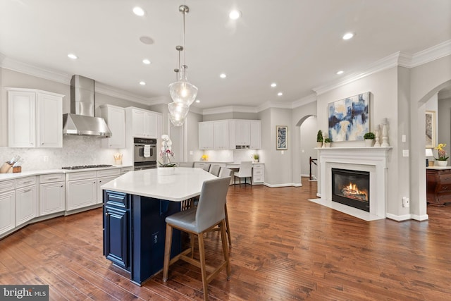 18729 Upper Meadow Dr, Leesburg, VA 20176 - kitchen with wall chimney exhaust hood, arched walkways, recessed lighting, gas cooktop, and a kitchen island