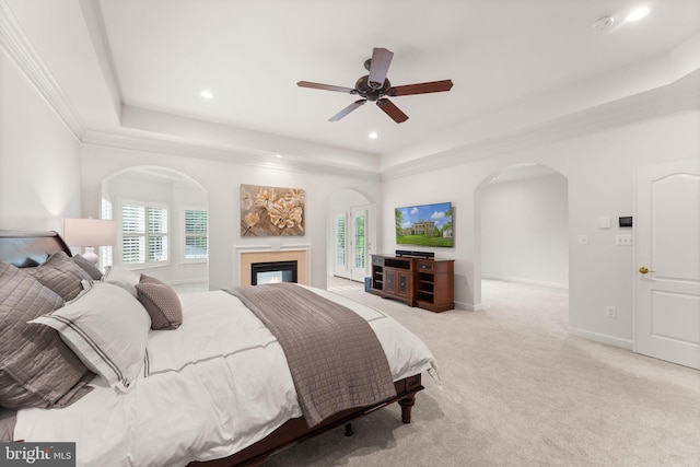18729 Upper Meadow Dr, Leesburg, VA 20176 - carpeted bedroom featuring a tray ceiling, arched walkways, a glass covered fireplace, recessed lighting, and ceiling fan