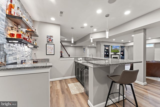 18729 Upper Meadow Dr, Leesburg, VA 20176 - kitchen with light wood-type flooring, a kitchen breakfast bar, light stone counters, a peninsula, and baseboards