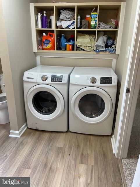 laundry area with separate washer and dryer, light wood-type flooring, and baseboards