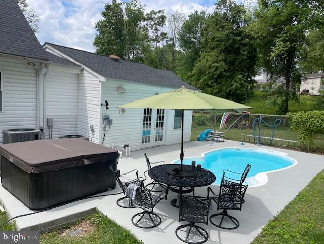 view of swimming pool featuring a hot tub, a patio area, fence, central air condition unit, and french doors