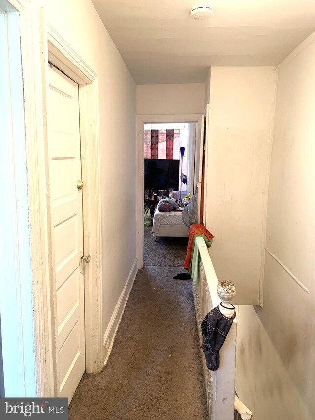 hallway featuring carpet flooring and baseboards