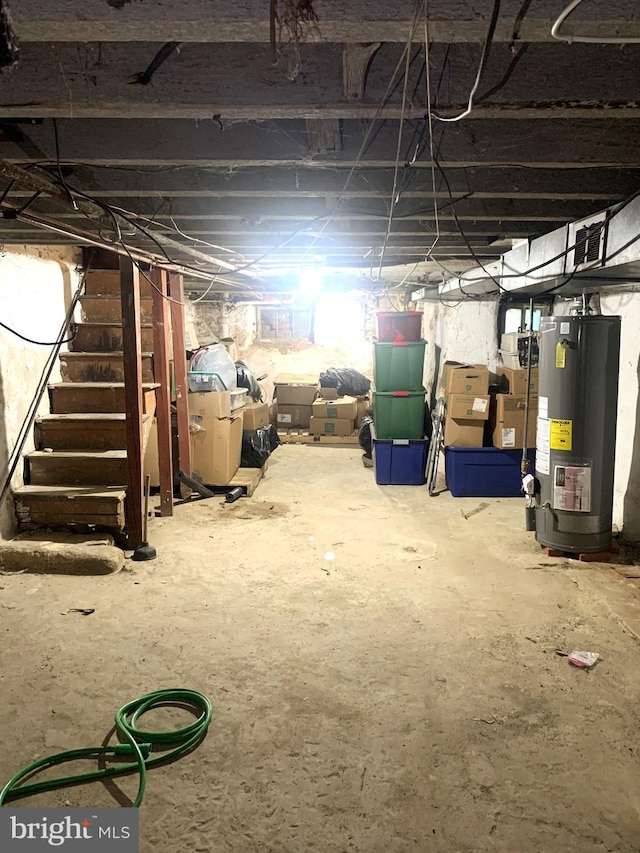 unfinished basement featuring water heater and stairs