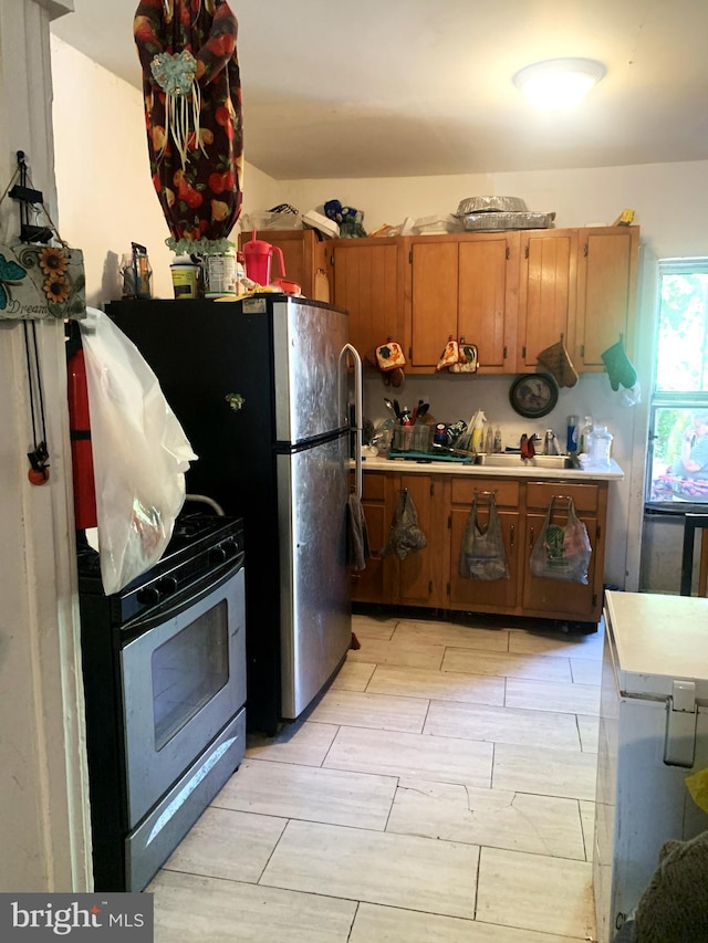 kitchen featuring stainless steel gas stove, light countertops, brown cabinets, and wood finish floors