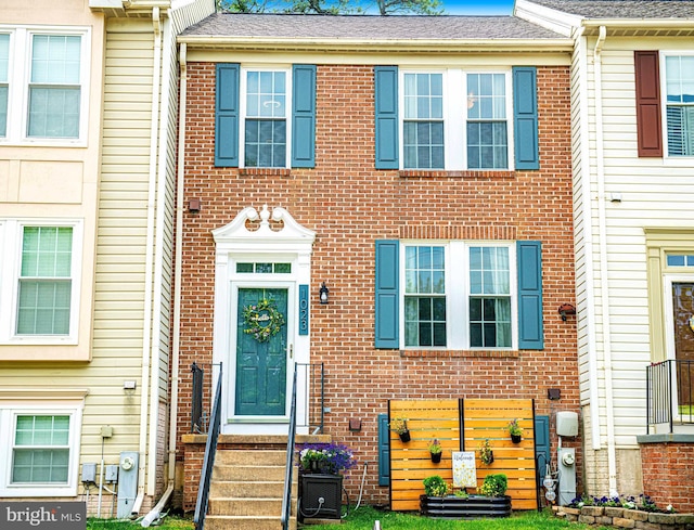 townhome / multi-family property featuring brick siding and roof with shingles