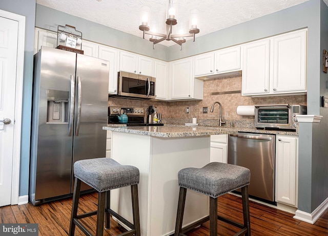 kitchen with appliances with stainless steel finishes, a sink, dark wood finished floors, white cabinetry, and a textured ceiling