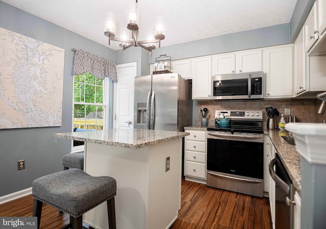 kitchen with appliances with stainless steel finishes, white cabinets, a center island, backsplash, and a textured ceiling