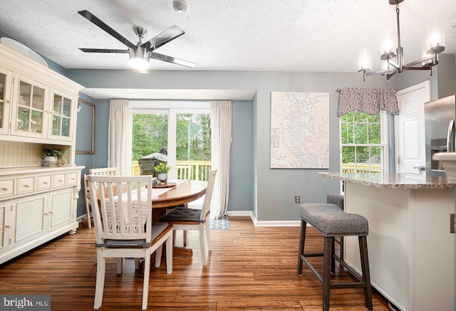 dining space with wood finished floors, a chandelier, baseboards, a textured ceiling, and ceiling fan