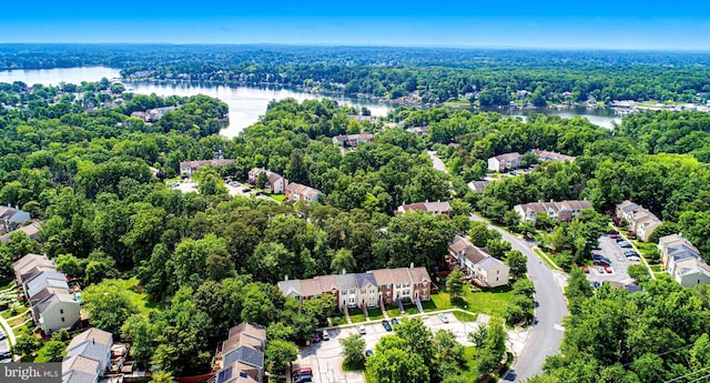 aerial perspective of suburban area with a nearby body of water and a heavily wooded area