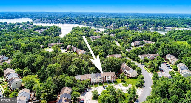 aerial perspective of suburban area featuring a nearby body of water and a heavily wooded area