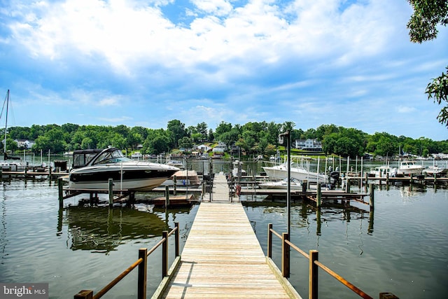 dock featuring boat lift, a water view, and view of scattered trees