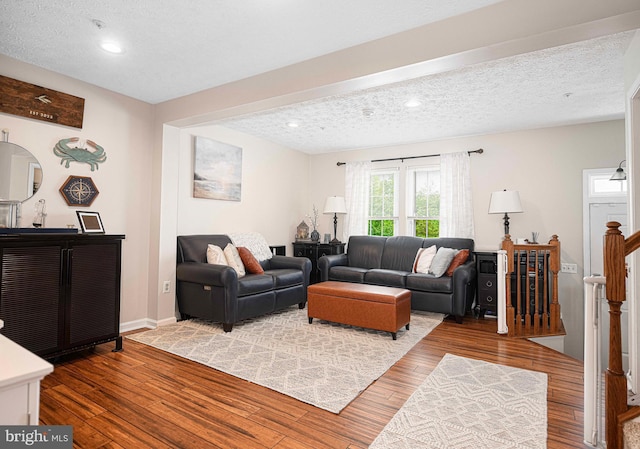 living room with wood finished floors, a textured ceiling, recessed lighting, and baseboards