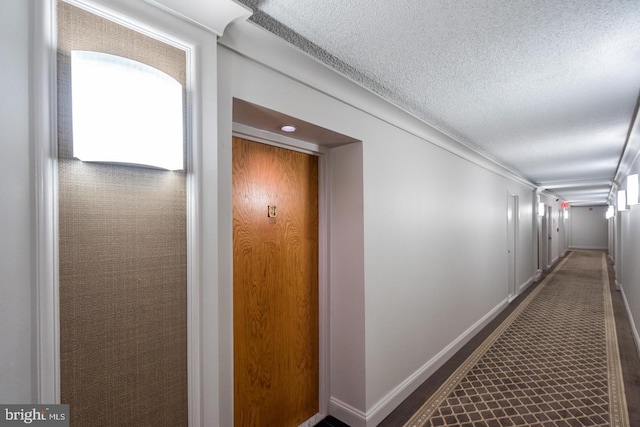hallway featuring a textured ceiling and baseboards