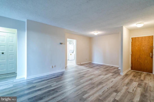 unfurnished living room with a textured ceiling, wood finished floors, and baseboards