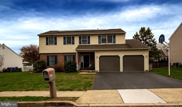 traditional-style home with roof mounted solar panels, driveway, central AC, a garage, and brick siding