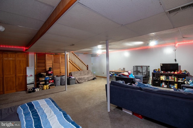 finished basement featuring carpet floors, stairs, and a drop ceiling