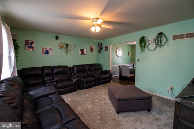 carpeted living area with ceiling fan and baseboards