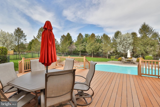deck with outdoor dining area and view of wooded area