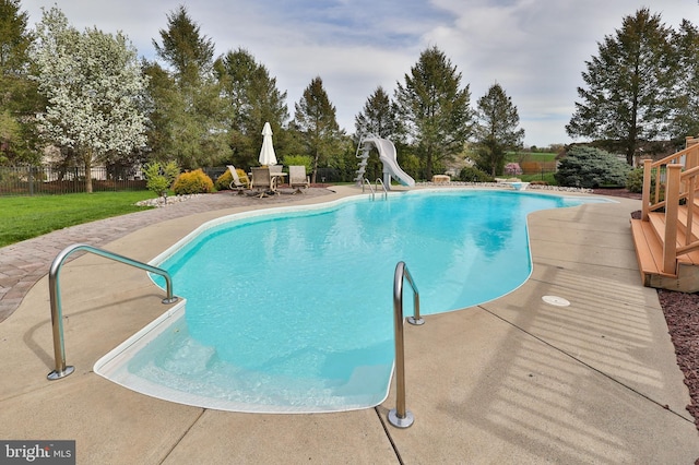 view of pool featuring a water slide, a patio area, and a diving board