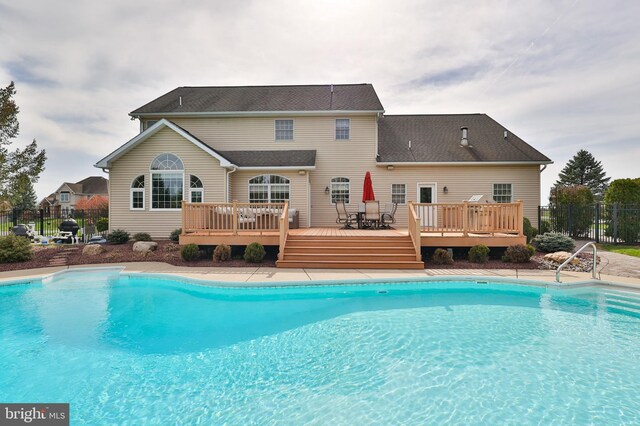 view of pool with a wooden deck, fence, and outdoor dining space