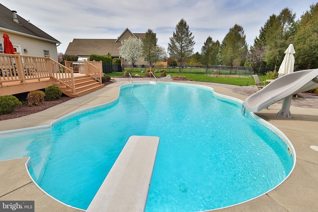 view of swimming pool featuring a water slide, a wooden deck, fence, and a diving board