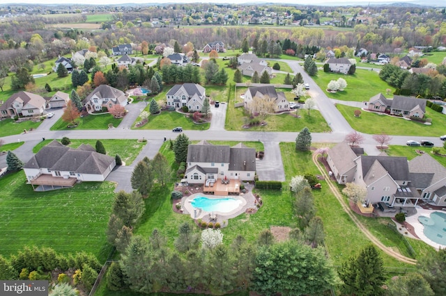 aerial view of property and surrounding area featuring a pool and nearby suburban area
