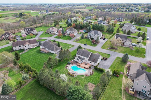 aerial view of property and surrounding area featuring a pool and nearby suburban area