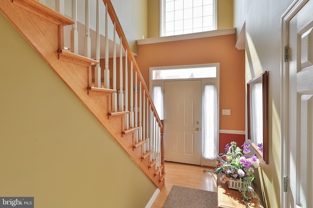 foyer entrance featuring a high ceiling, wood finished floors, and stairway