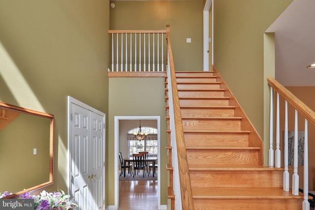 stairway featuring a high ceiling, a chandelier, and wood finished floors
