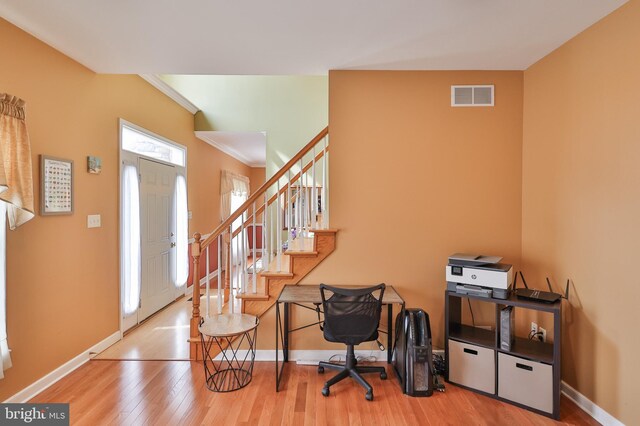 entryway with wood finished floors, baseboards, crown molding, and stairs