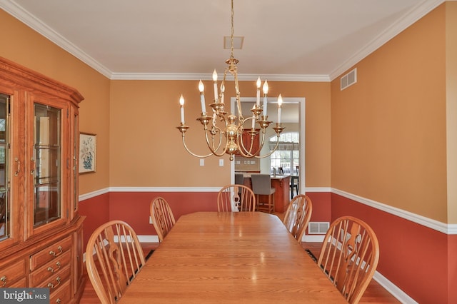 dining space featuring a chandelier, ornamental molding, baseboards, and wood finished floors
