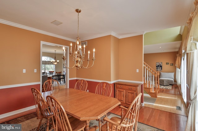 dining space featuring wood finished floors, a chandelier, stairway, ornamental molding, and baseboards