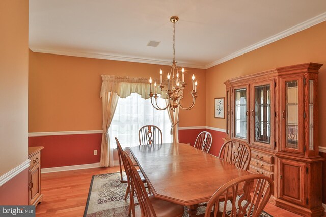 dining area featuring a chandelier, light wood finished floors, ornamental molding, and baseboards