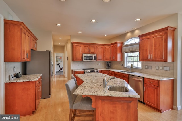 kitchen with stainless steel appliances, a sink, decorative backsplash, light wood finished floors, and recessed lighting