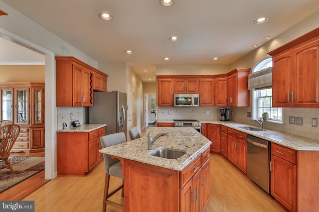 kitchen with appliances with stainless steel finishes, a sink, tasteful backsplash, light wood-style flooring, and recessed lighting