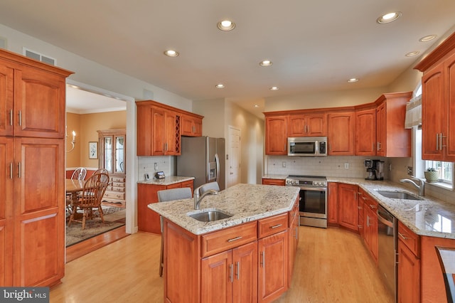 kitchen featuring appliances with stainless steel finishes, a sink, a center island, light wood-style flooring, and recessed lighting