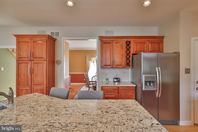 kitchen with stainless steel fridge, light stone countertops, decorative backsplash, baseboards, and recessed lighting