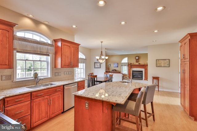 kitchen with stainless steel dishwasher, light wood-style floors, a sink, recessed lighting, and a kitchen island with sink