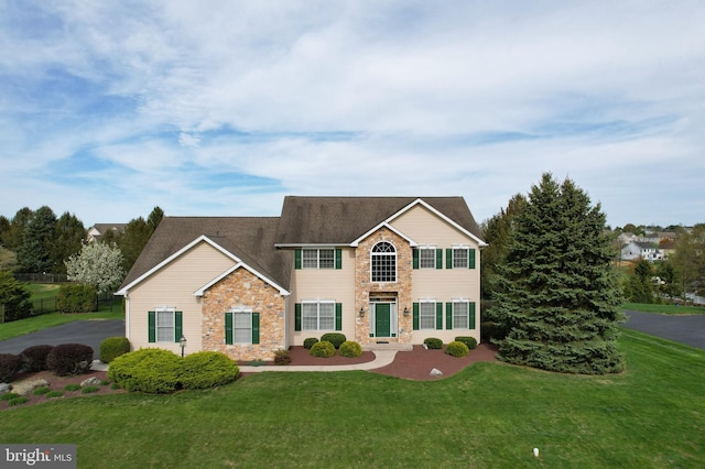 view of front of house with stone siding, a front lawn, and roof with shingles