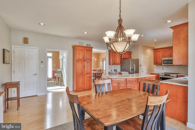 dining area featuring a chandelier, light wood-style flooring, recessed lighting, and baseboards