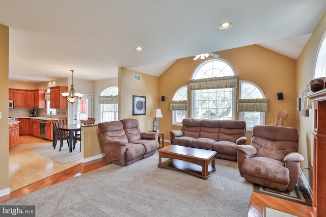 living room featuring light wood-style flooring, a chandelier, plenty of natural light, lofted ceiling, and recessed lighting