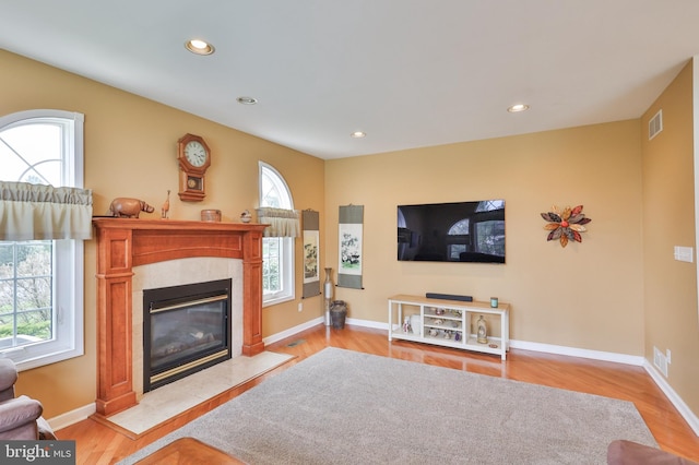living room featuring a premium fireplace, wood finished floors, recessed lighting, and baseboards