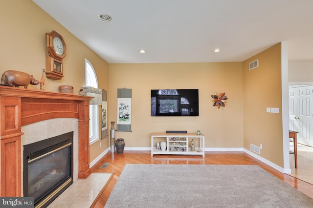 living room featuring a tile fireplace, recessed lighting, light wood-type flooring, and baseboards