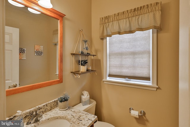 half bathroom with plenty of natural light, toilet, and vanity