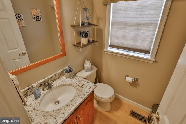 bathroom with baseboards, wood finished floors, toilet, and vanity