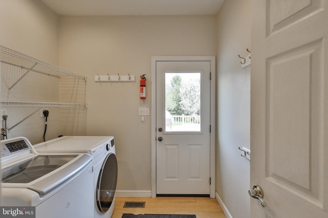 clothes washing area featuring independent washer and dryer, light wood-type flooring, and baseboards