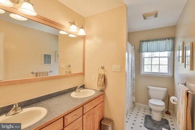 full bathroom featuring toilet, double vanity, and baseboards