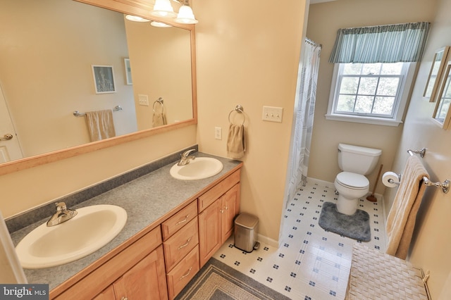 bathroom featuring toilet, baseboards, and double vanity