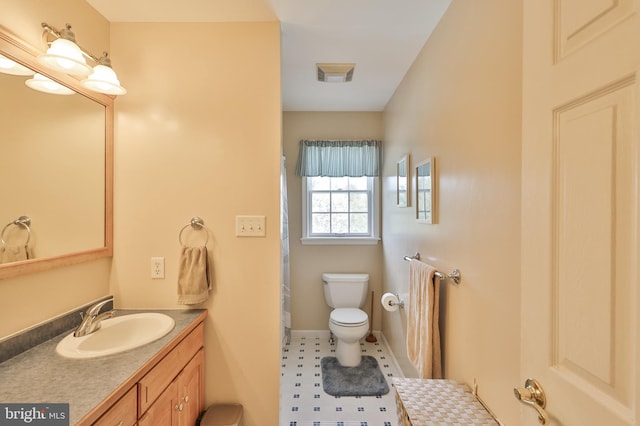 bathroom featuring toilet, vanity, and baseboards