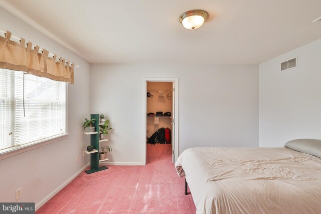bedroom featuring a spacious closet, light carpet, a closet, and baseboards